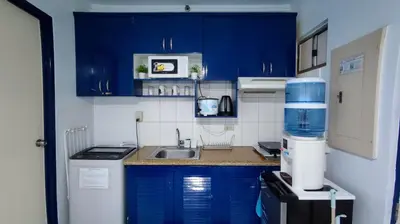 a small kitchen with blue cabinets and a sink at Near Manila Airport, MAILZ HOMEZ COZY 1 Bedroom Condo, Full Kitchen, Swimming Pool, WIFI, 10L in Manila