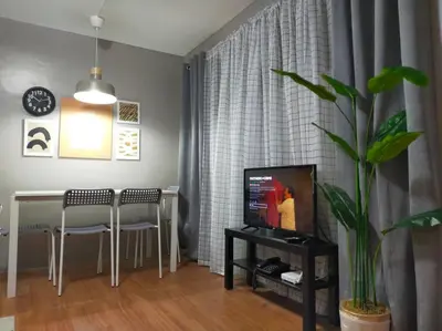 a living room with a television and a table with chairs at Stylish 2BR w/ Free Pool Access and Parking LG03 in Manila