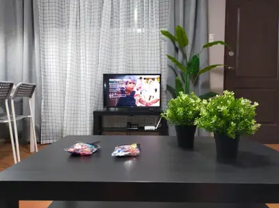 a living room with a table with a tv and plants at Stylish 2BR w/ Free Pool Access and Parking LG03 in Manila