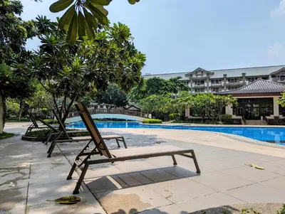 a wooden bench sitting next to a swimming pool at Acacia Estates' The Getaway Taguig Jade Tower in Manila
