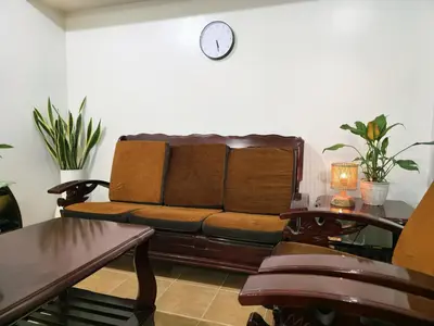 a living room with a couch and a clock on the wall at Acacia Estates' The Getaway Taguig Jade Tower in Manila