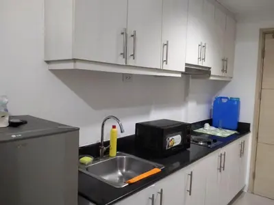 a kitchen counter with a sink and a microwave at MOA Staycation - Ashti in Manila