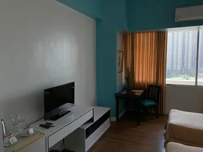 a hotel room with a television and a bed and a desk at Pearl Manila Hotel in Manila