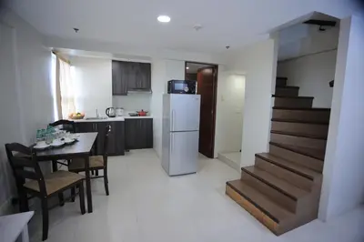 a kitchen and dining room with a table and a staircase at Homes by Gilmore Tower Suites in Manila