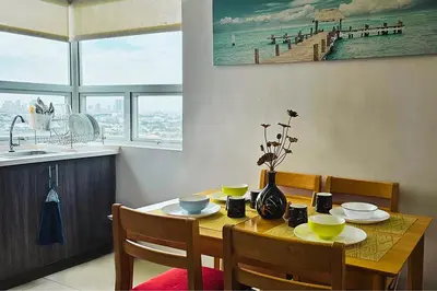 a dining room with a table with chairs and a pier at Homes by Gilmore Tower Suites in Manila