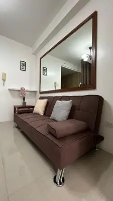 a brown couch in a living room with a large mirror at Shore Residences in Manila