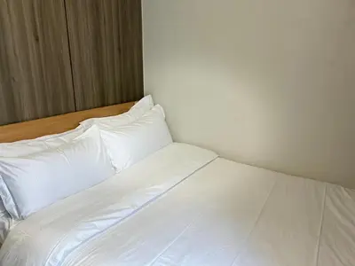 a bed with white sheets and pillows in a room at Cairong Inn Condominium TV with Netflix FAME RESIDENCES in Manila