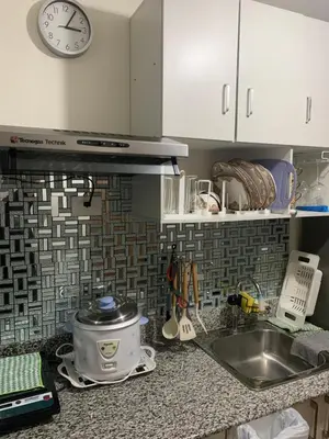 a kitchen counter with a sink and a clock on the wall at PARANAQUE STAYCATION at SPRING RESIDENCES T3 U1231 in Manila