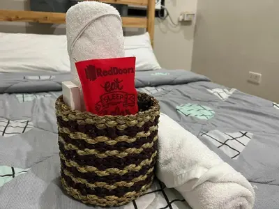 a basket filled with towels on top of a bed at P3K Suites Budget Hotel in Manila