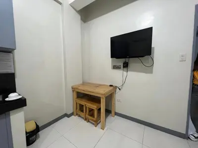 a room with a small table and a tv on a wall at P3K Suites Budget Hotel in Manila