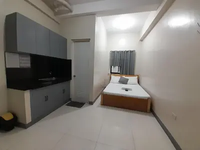 a small white room with a bed and a tv at P3K Suites Budget Hotel in Manila