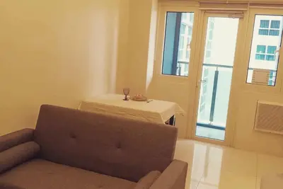 a living room with a couch and a table and a window at Homey 1Bedroom BGC Condo - MINIMUM 2 Nights stay in Manila
