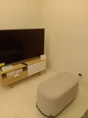 a living room with a television and a ottoman at Homey 1Bedroom BGC Condo - MINIMUM 2 Nights stay in Manila
