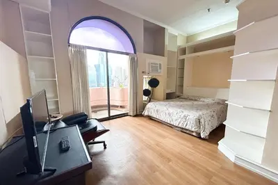a bedroom with a bed and a desk with a television at Sunette Tower Suites Makati City Center in Manila