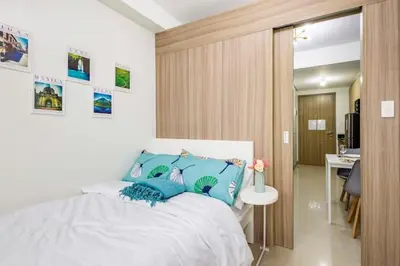 a bedroom with a bed with blue pillows at Shore 2 Residences 1BR Deluxe Room in MOA Complex in Manila