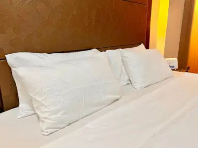 a bed with white sheets and pillows on it at Newport Hotel near NAIA Manila Airport Terminal Pasay in Manila