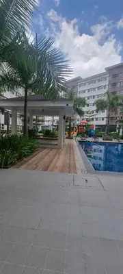 a large building with a pool and a palm tree at Auberge Condotels at SMDC Hope Residences in Trece Martires