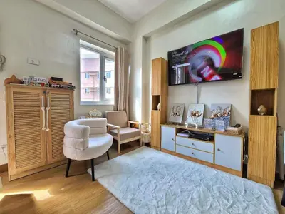 a living room with a chair and a tv at Auberge Condotels at SMDC Hope Residences in Trece Martires