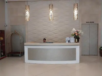 a man sitting at a reception desk in a lobby at Alps Guesthouse at 150 Newport Blvd near T3 in Manila