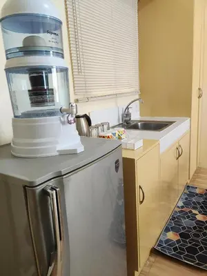 a kitchen with a coffee maker on top of a refrigerator at Near Manila Airport, MAILZ HOMEZ COZY Studio Condo, Full Kitchen, Swimming Pool, WIFI, 11P in Manila
