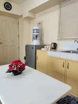 a kitchen with a table with a vase of flowers on it at Near Manila Airport, MAILZ HOMEZ COZY Studio Condo, Full Kitchen, Swimming Pool, WIFI, 11P in Manila
