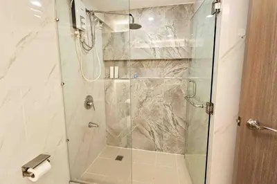 a shower with a glass door in a bathroom at Stylish 2 Bedroom Condo Near BGC and Airport with Fast WiFi in Manila