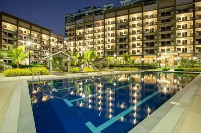 a hotel with a swimming pool in front of a building at Stylish 2 Bedroom Condo Near BGC and Airport with Fast WiFi in Manila