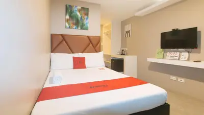 a bedroom with a large bed with a tv at RedDoorz Plus at Seventy Five Inn Near Manila Airport in Manila