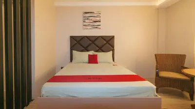 a bedroom with a bed with a red pillow on it at RedDoorz Plus at Seventy Five Inn Near Manila Airport in Manila