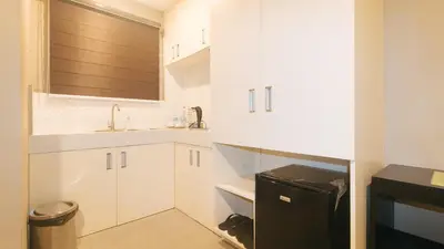 a kitchen with white cabinets and a black refrigerator at RedDoorz Plus at Seventy Five Inn Near Manila Airport in Manila