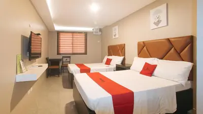 a hotel room with two beds and a table at RedDoorz Plus at Seventy Five Inn Near Manila Airport in Manila