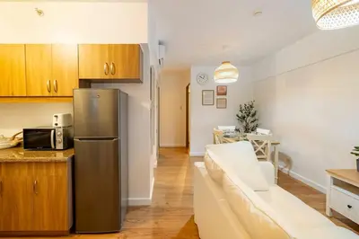 a kitchen and a living room with a stainless steel refrigerator at Bohemian Inspired 2 Bedroom Inspired Condo with Fast WIFI Near BGC in Manila