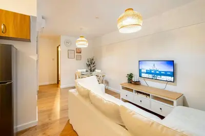 a living room with a white couch and a flat screen tv at Bohemian Inspired 2 Bedroom Inspired Condo with Fast WIFI Near BGC in Manila