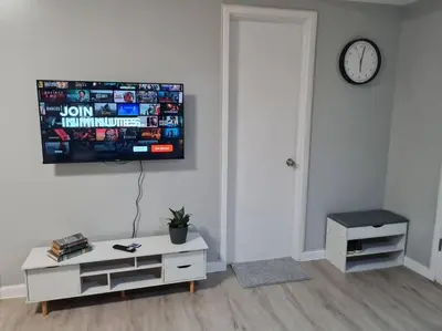 a living room with a tv on a white wall at Homey condo unit in BGC - B SOMA NT in Manila
