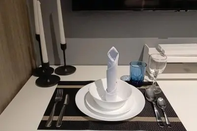 a table with a plate with a napkin on it at Cozy New 1BR Fame Residences Condo with Balcony in Manila