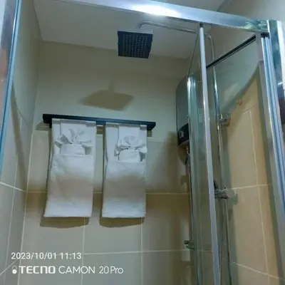 a bathroom with towels on a rack and a shower at Cozy New 1BR Fame Residences Condo with Balcony in Manila