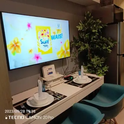 a room with a tv and two chairs and a table at Cozy New 1BR Fame Residences Condo with Balcony in Manila