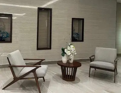a living room with two chairs and a table with a vase of flowers at CozyCoastStay by APPLETRAVELBEYONDPH in Manila