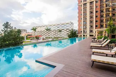a large swimming pool with lounge chairs and a building at Monarch Parksuites - Balmoral Place (near NAIA, MOA, MOA Arena, DFA) in Manila