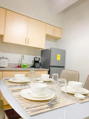 a kitchen with a table with plates and dishes on it at Deluxe Room w/ Pool & Billiards in Manila