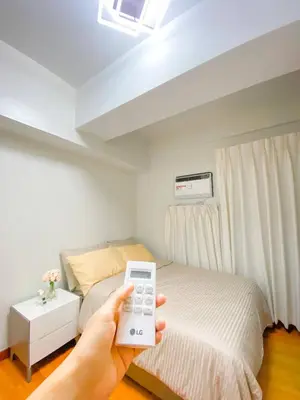 a person holding a remote control in front of a bed at Deluxe Room w/ Pool & Billiards in Manila