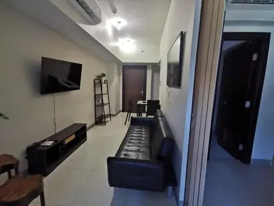 a living room with a couch and a flat screen tv at Caleze Properties Uptown Palazzo BGC One Bedroom in Manila