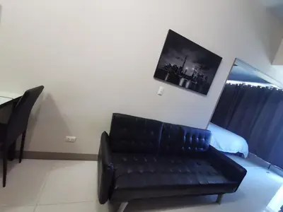 a black leather couch in a room with a bed at Caleze Properties Uptown Palazzo BGC One Bedroom in Manila