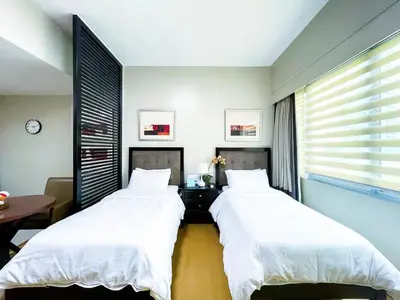 two beds in a room with a table and a window at Hotel like unit The Avant at the Fort in Manila