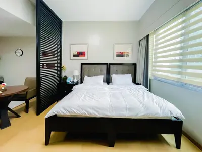 a bedroom with a bed and a table and a desk at Hotel like unit The Avant at the Fort in Manila
