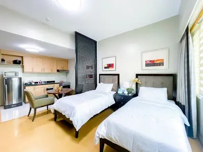 a bedroom with two beds and a table and a kitchen at Hotel like unit The Avant at the Fort in Manila