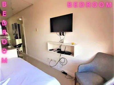 a bedroom with a bed and a tv on the wall at Need Place To Stay Booked Now Manila with Balcony Sea View, Promo Discount, Free Pool Plus Free Sauna Access Steps Away US Embassy, Updated 2026 Prices - Hurry Limited Time Only in Manila