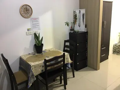 a table and chairs with a table and a clock on the wall at Shore residences Ph in Manila