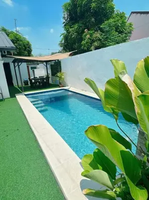 a swimming pool with green grass and a house at Sönmez Private Villa in Cavite