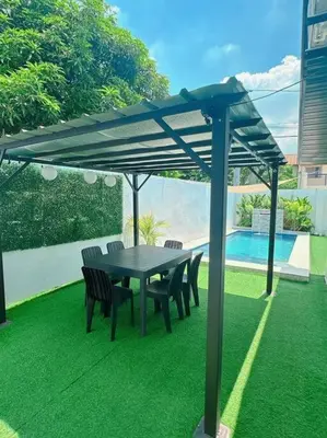 a table and chairs under an umbrella on the grass at Sönmez Private Villa in Cavite